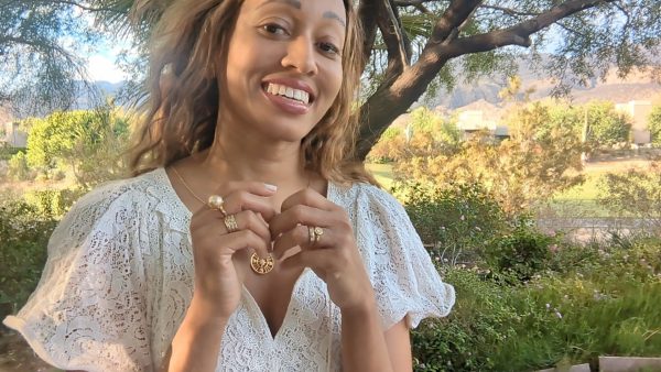 black woman smiling in garden wearing white dress and smiling while wearing the Large oversized South sea pearl diamond ring from the wandering jewel