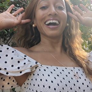 black woman on Greek island in a polka dot dress wearing large gold South sea pearl diamond earring studs from the wandering jewel