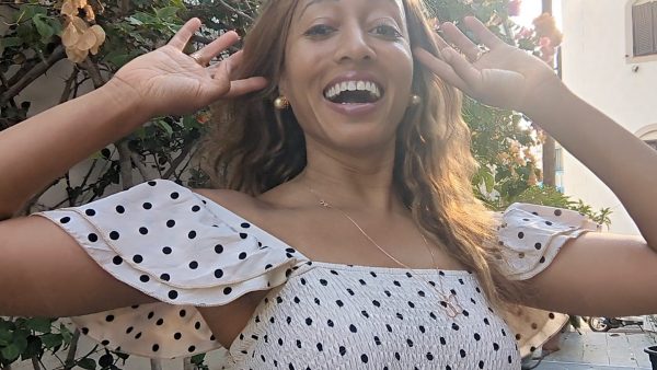 black woman on Greek island in a polka dot dress wearing large gold South sea pearl diamond earring studs from the wandering jewel