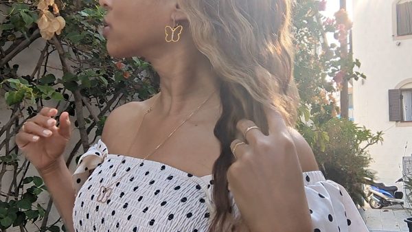 black woman in polka dot dress on a street in Greece wearing the 7 diamond butterfly earrings and necklace from the wandering jewel