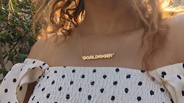 woman in polka dot dress wearing the gold goal digger necklace from the wandering jewel