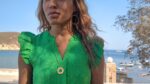 black woman in green dress in marina wearing Rose gold star of David pendant necklace coin from the wandering jewel