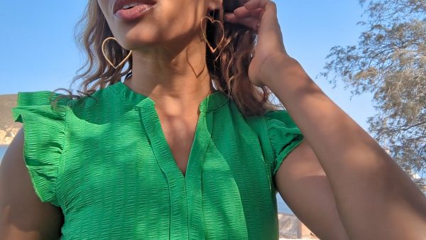 woman in a green dress wearing large gold hoop earrings shaped like a heart from the wandering jewel