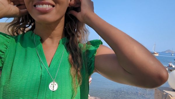 black women in harbor wearing a green dress and the cross coin cutout pendant from the wandering jewel