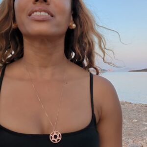 black woman on beach in black bikini wearing the Rose gold star of David pendant necklace coin from the wandering jewel