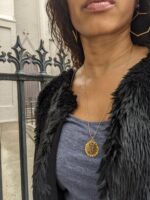 black woman with curly hair in blue dress and fur necklace wearing the 7 diamond Semper Fi Coin Pendant necklace from the wandering jewel, new orleans