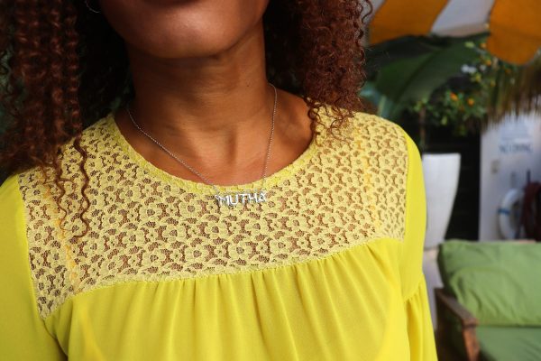 woman in yellow dress at pool wearing mutha mother necklace from the wandering jewel