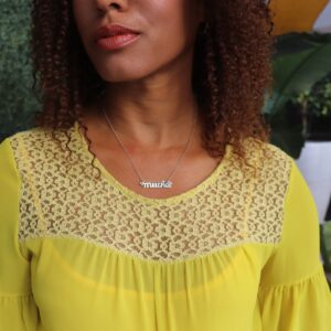 black woman with curly hair in a yellow dress at pool wearing silver mutha mother necklace from the wandering jewel