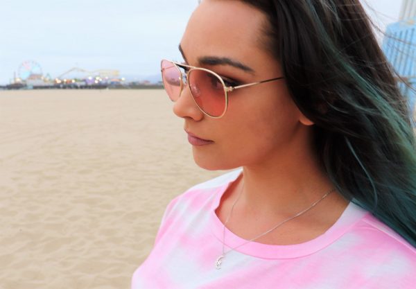 woman at beach with sunglasses and pink tie-dye shirt wearing sun and moon diamond pendant from the wandering jewel