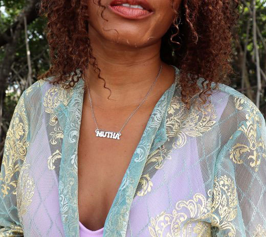 black women in Forrest wearing a blue and purple robe and a silver Mutha necklace from the wandering jewel