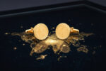 gold AI star patterned cufflinks resting on a black marble table with a map of the world outlined in gold ink