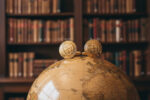 Gold Interweb cufflinks from the wandering jewel sitting on top of a globe in a library